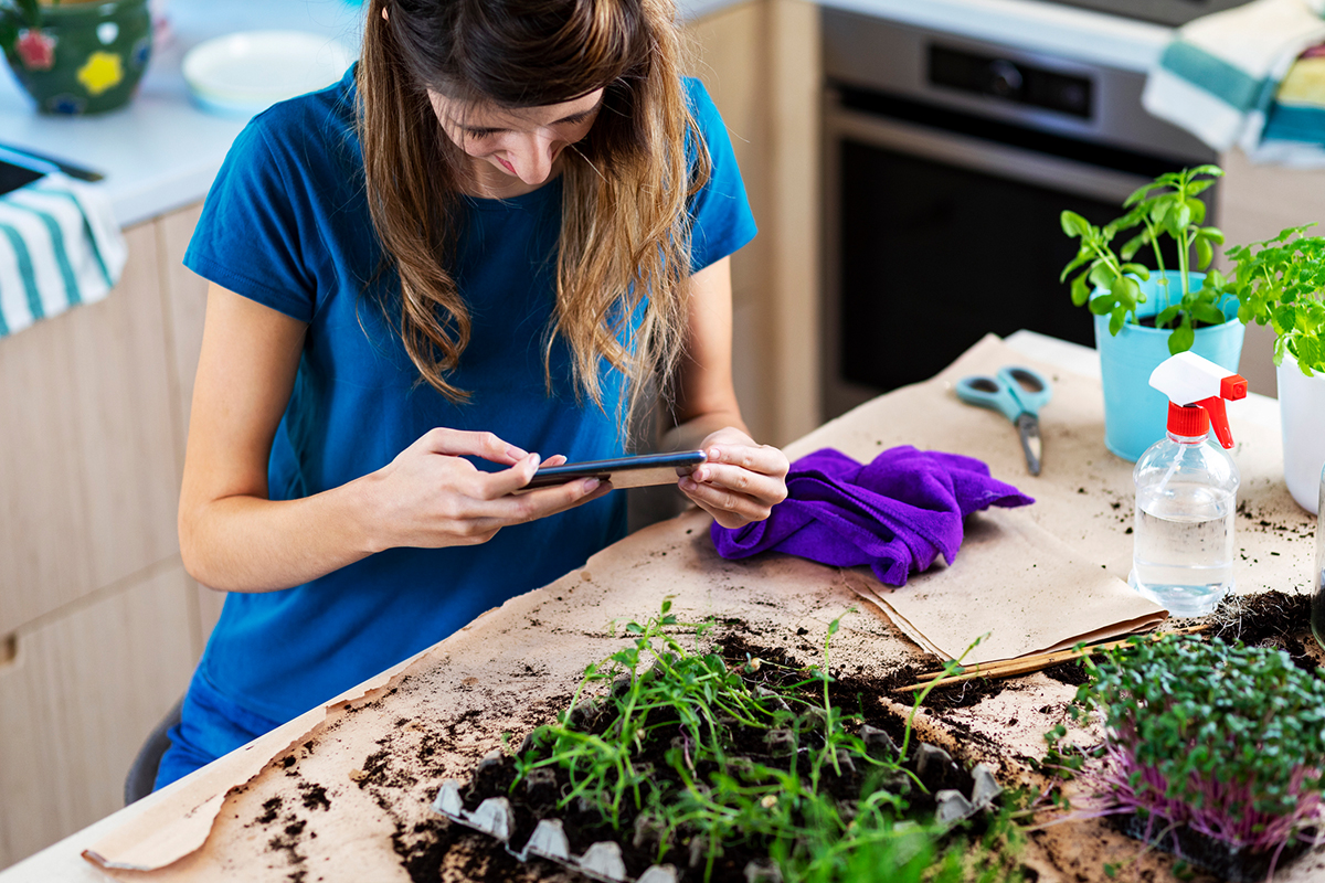 Mulher praticando jardinagem enquanto tira foto para Instagram