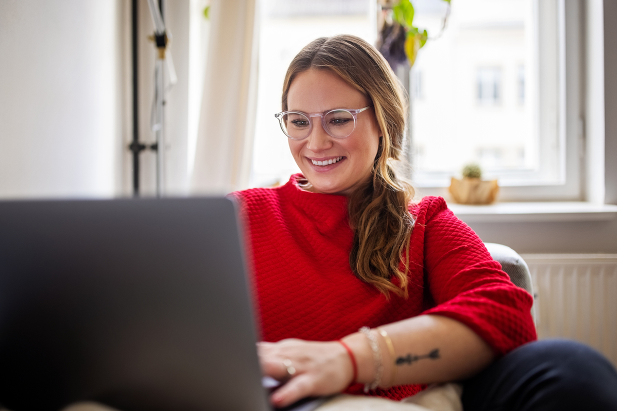 Mulher sorridente, pesquisando em um notebook sobre como ganhar dinheiro na internet