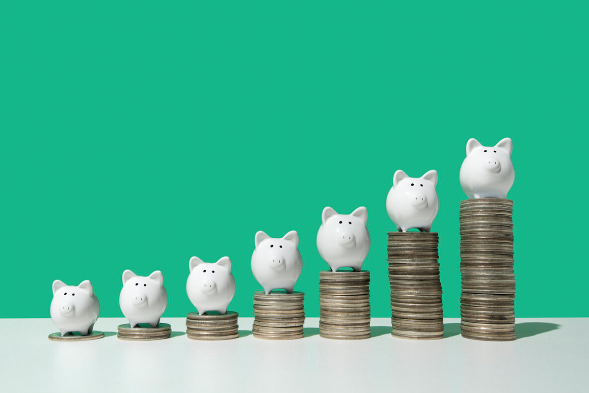 Escada de pilhas de moedas com cofres de porquinho em cima em ordem crescente para representar o empréstimo para MEI.